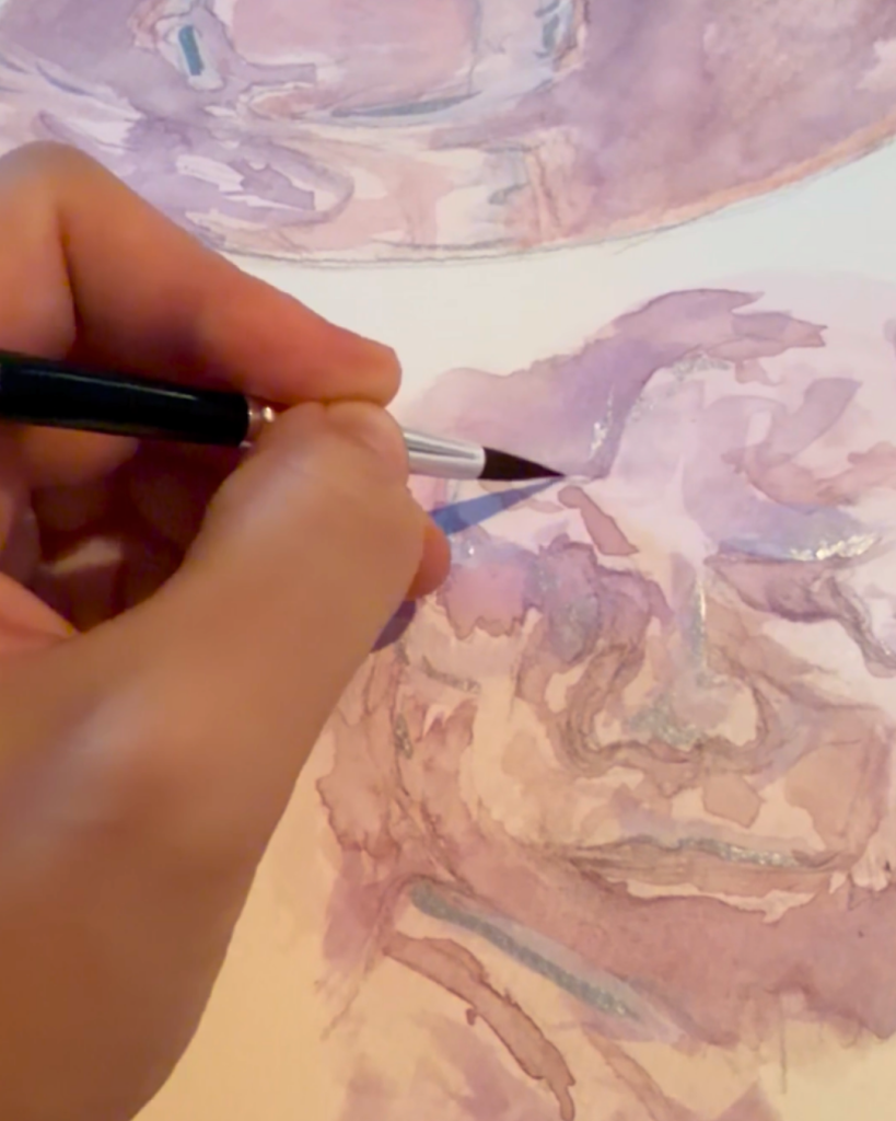 Hand holding a paintbrush over a watercolor painting of a 3D ultrasound with soft, pastel colors.