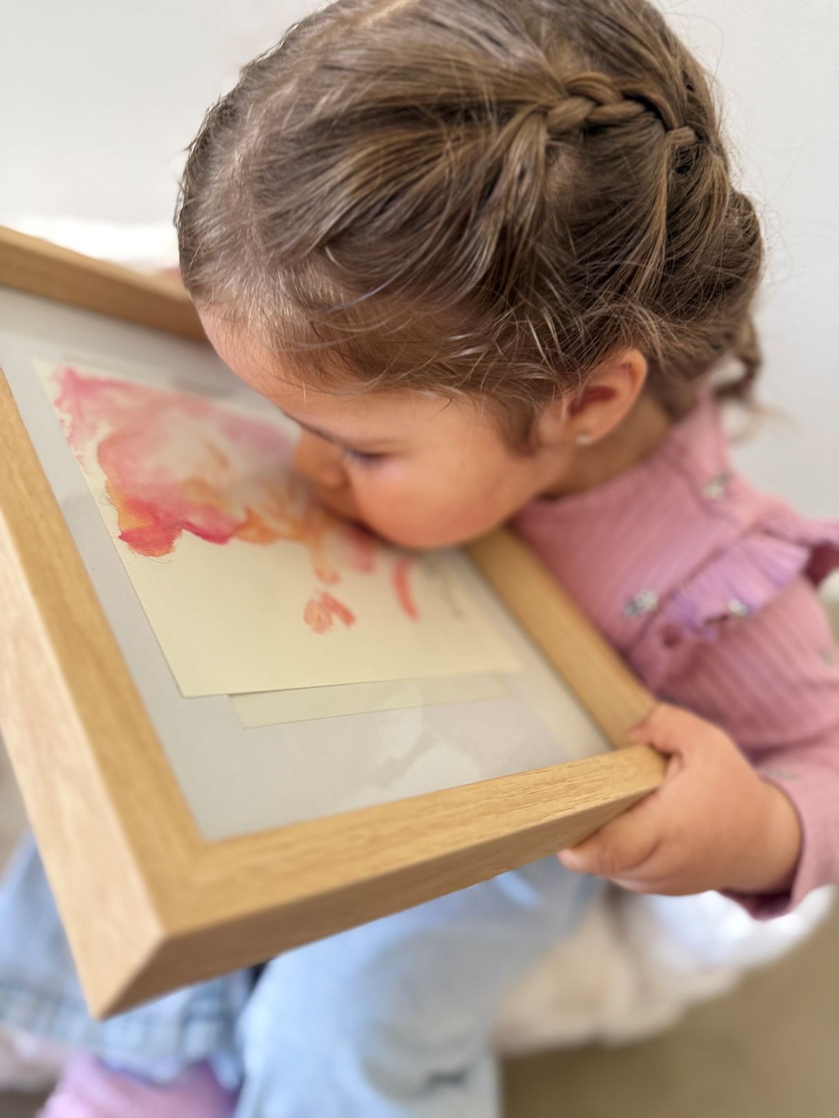 Child holding a framed picture of a pink 3d 4d ultrasound