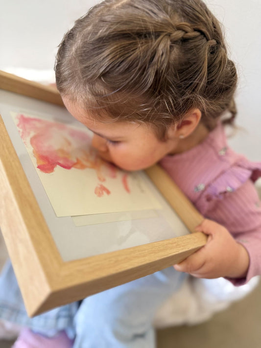Child holding a framed picture of a pink 3d 4d ultrasound