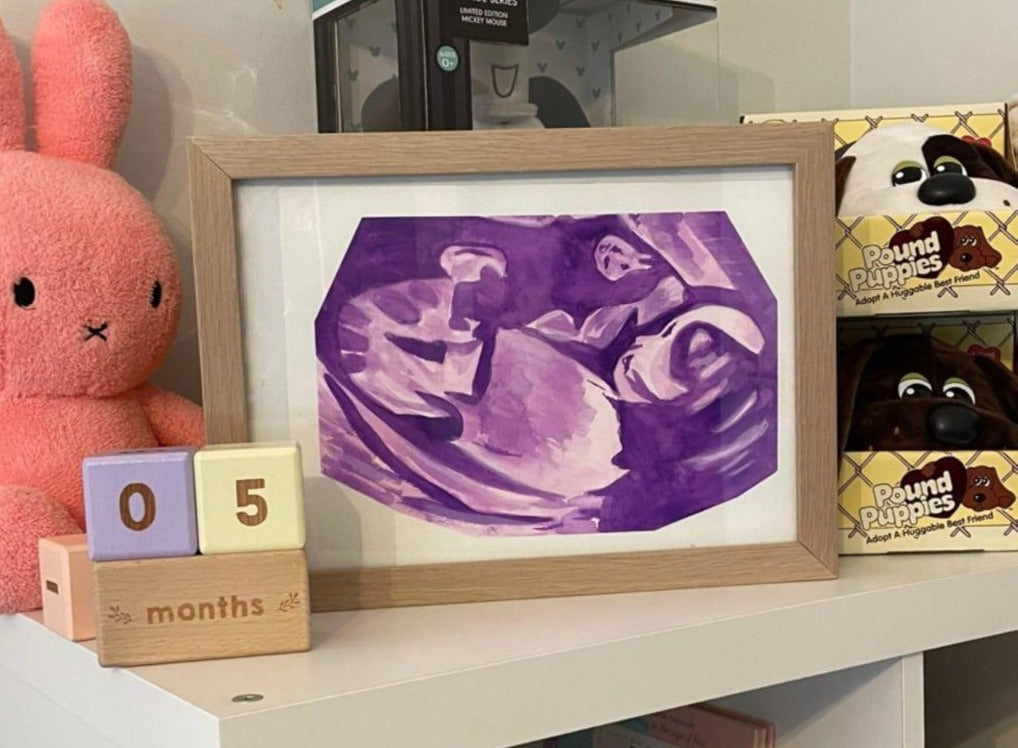 Framed ultrasound image of a baby with a pink teddy bear and toy boxes on a shelf.