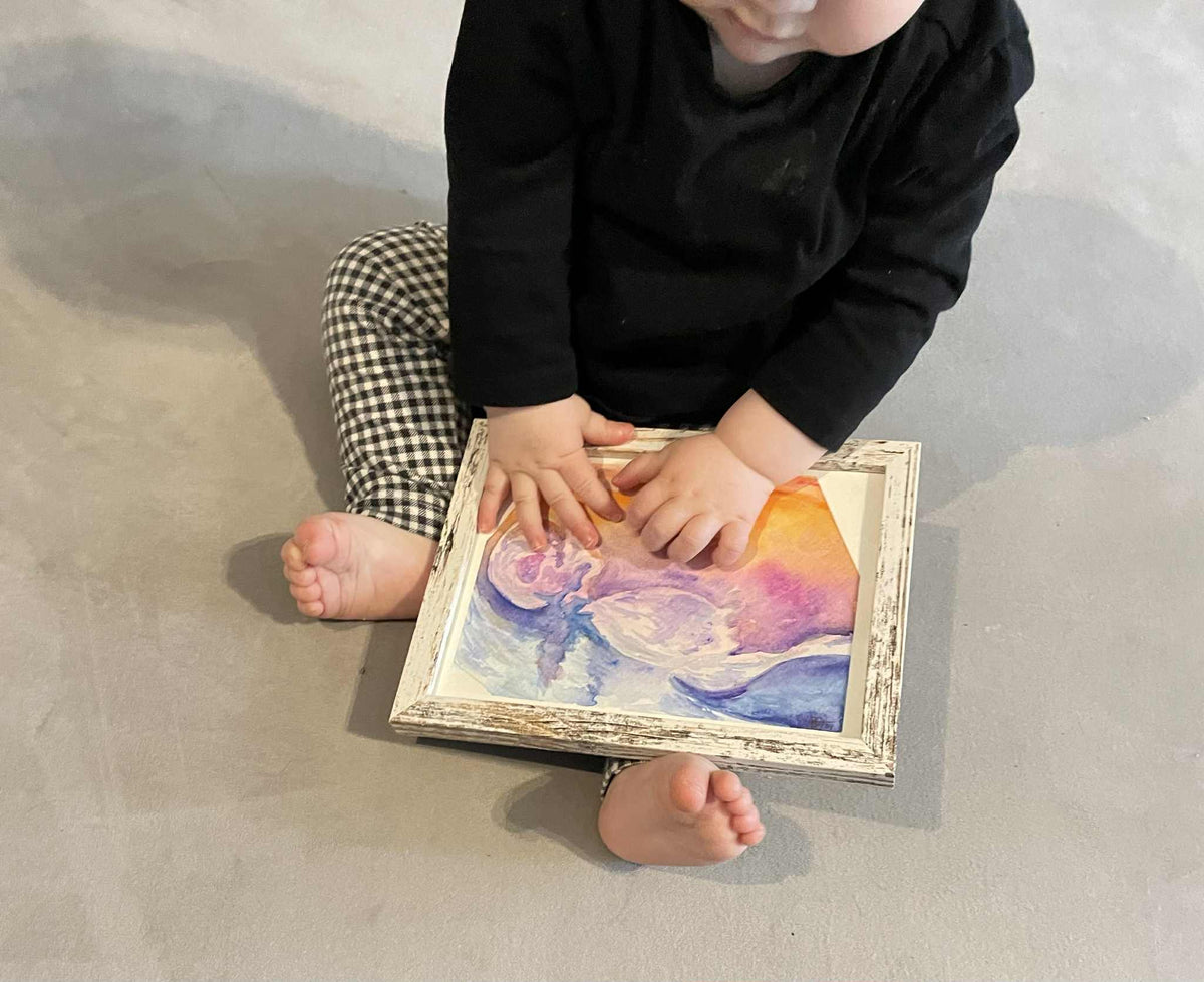 child holding their framed ultrasound painting in orange pink and blue