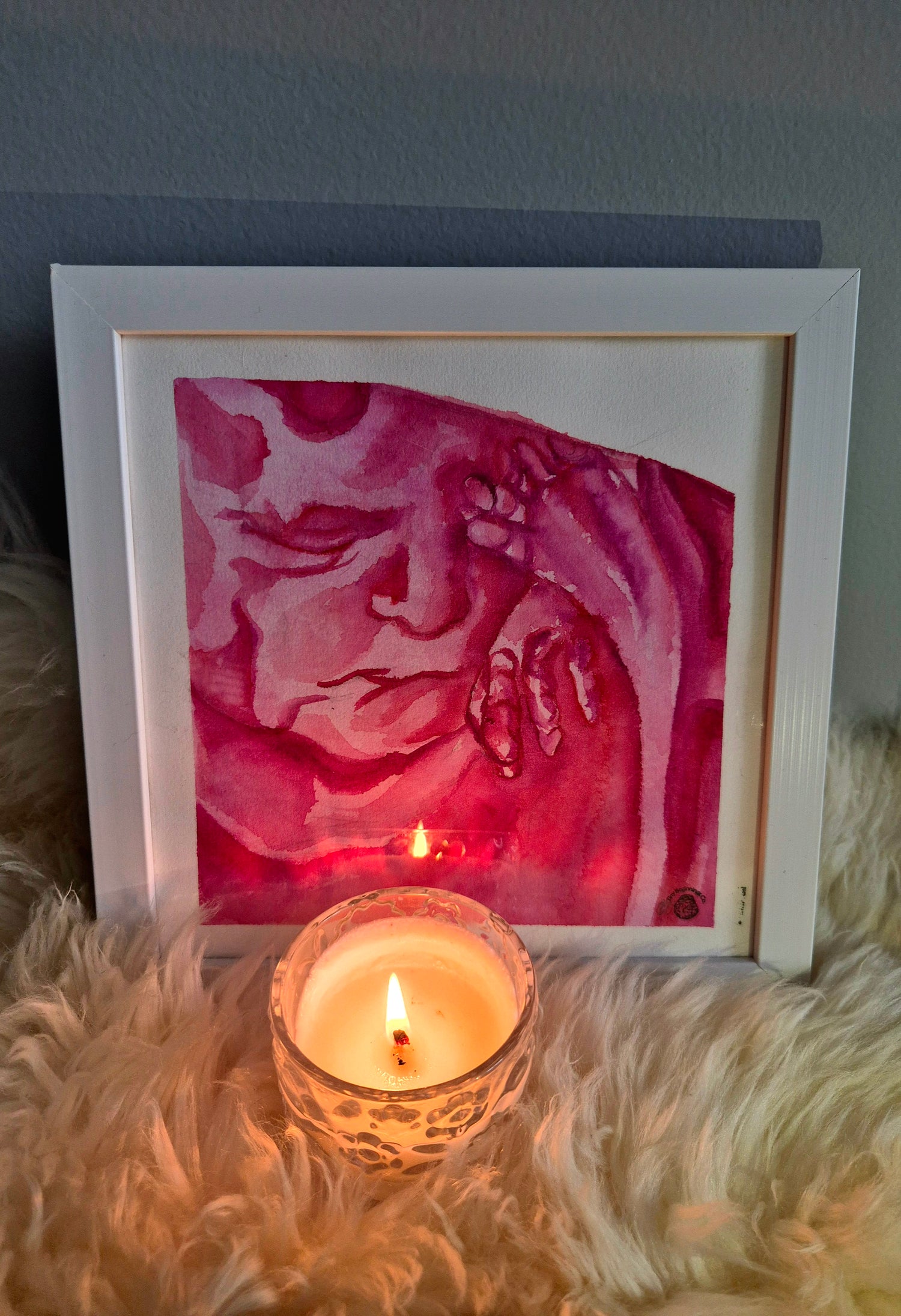 framed pink 3d 4d watercolour ultrasound painting with a lit candle