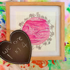 Heart-shaped chalkboard with 'we are 1 in 4' text, framed ultrasound and elephant artwork, and colorful watercolor background