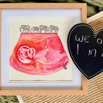 Framed artwork with a pink fetus illustration and elephants, next to a heart-shaped sign.