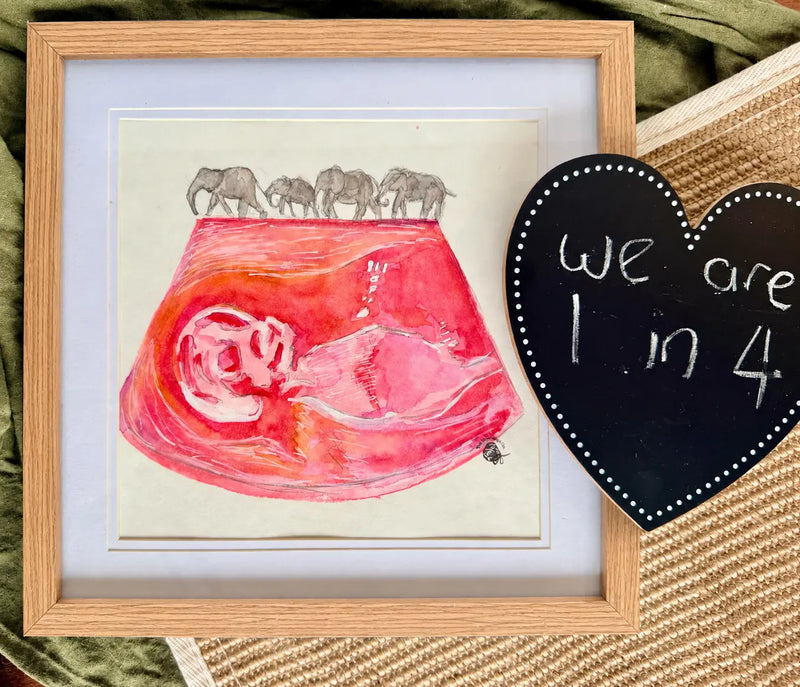 Framed artwork with a pink fetus illustration and elephants, next to a heart-shaped sign.