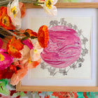 Framed artwork with a pink ultrasound circle and gray elephant border, surrounded by colorful flowers.
