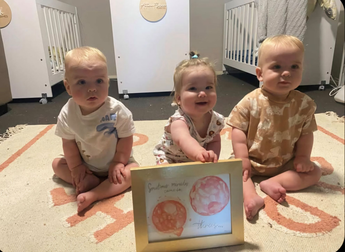 triplets with their framed embryo painting